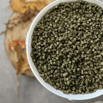 Balão branco com pellets verdes com textura granulada em fundo cinza e planta seca.