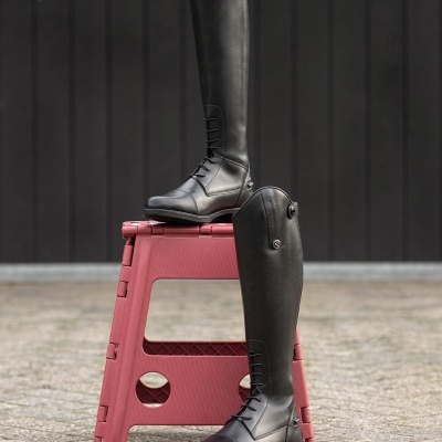 Botas altas pretas em pele com atacadores sobre banco vermelho