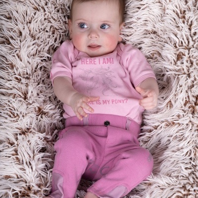 Bebé com roupa rosa deitado numa manta felpuda bege