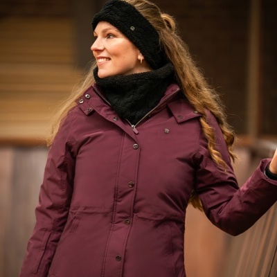 Mulher com casaco vinho e acessórios de inverno pretos, sorridente