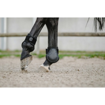 Proteção preta nas pernas de cavalo em picadeiro de areia