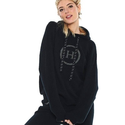 Mulher a usar conjunto preto com capuz e calças com logótipo 'H' no peito