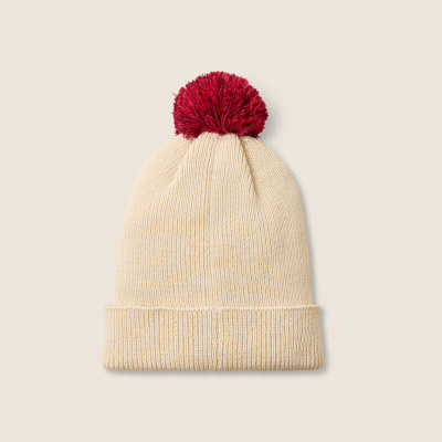 Gorro creme com pompom vermelho sobre fundo neutro