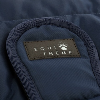 Etiqueta de couro castanho com texto 'EQUI THEME' em tecido azul escuro
