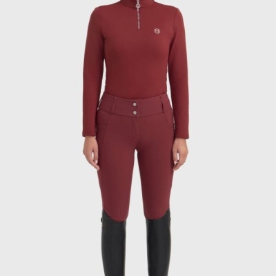 Mulher com roupa desportiva bordô, boné e botas pretas em fundo branco