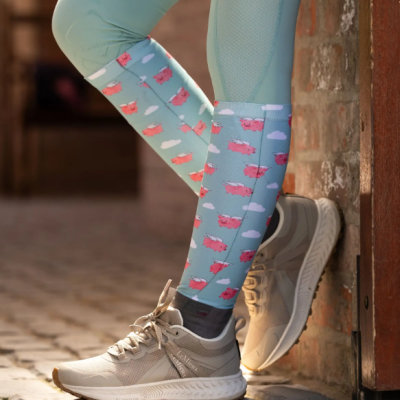 Meias azuis com porquinhos cor-de-rosa e nuvens brancas, usadas com leggings azuis e ténis bege