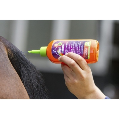 Frasco laranja com tampa verde e rótulo roxo usado na crina de cavalo castanho