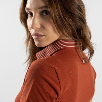 Camisola polo laranja queimado com gola e punhos com riscas finas brancas vista de perfil