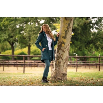 Mulher com casaco verde escuro junto a árvore num parque