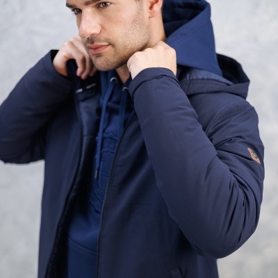 Homem a usar casaco azul escuro com capuz, com bolso lateral e detalhes em couro no braço