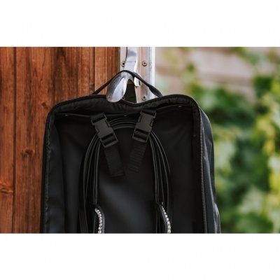 Mochila preta aberta pendurada numa maçaneta de porta de madeira