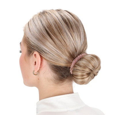 Mulher com cabelo loiro preso num coque com elástico cor de rosa e brinco dourado.