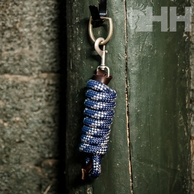 Corda trançada azul e branca com acabamento em couro castanho pendurada numa porta verde