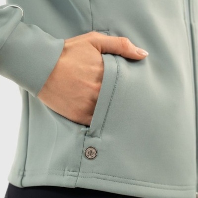 Close-up de mão em bolso de roupa desportiva verde-acinzentada junto a calças pretas