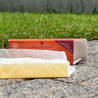 Barra de sabão amarela da marca Carr & Day & Martin com embalagem laranja sobre pavimento e relva