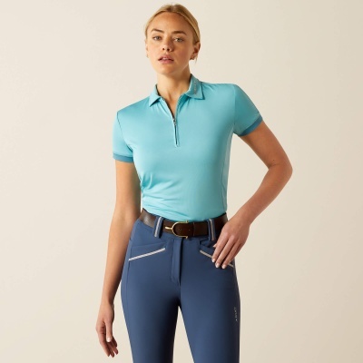 Mulher com polo azul-claro e calças azul-escuro num fundo bege