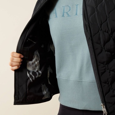 Casaco preto acolchoado aberto mostrando forro com padrão de cavalos e camisola azul por baixo