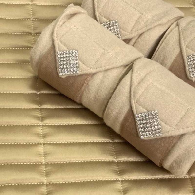 Almofadas bege com cristais quadrados sobre manta acolchoada bege
