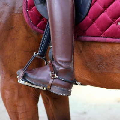 Bota de montaria castanha com estribo em cavalo castanho e manta vermelha