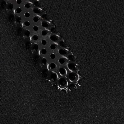 Detalhe de objeto preto perfurado sobre fundo preto