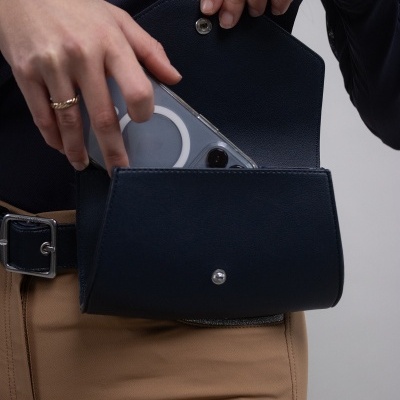 Pessoa a guardar telemóvel numa mala de mão preta com fecho metálico.