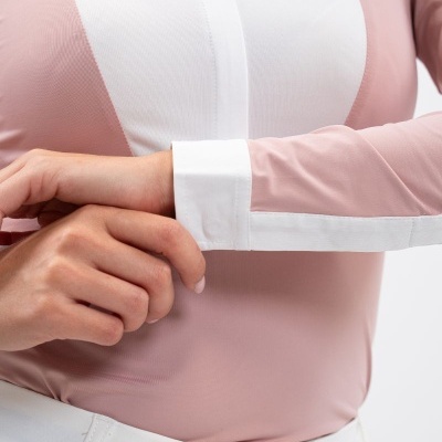 Blusa rosa e branca de manga comprida com punho branco junto a calças brancas.