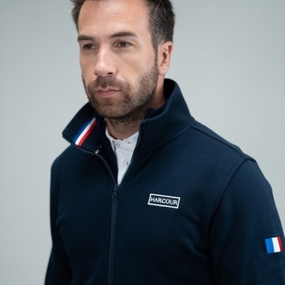 Homem com casaco azul escuro com logótipo HARCOUR e bandeira da França na manga