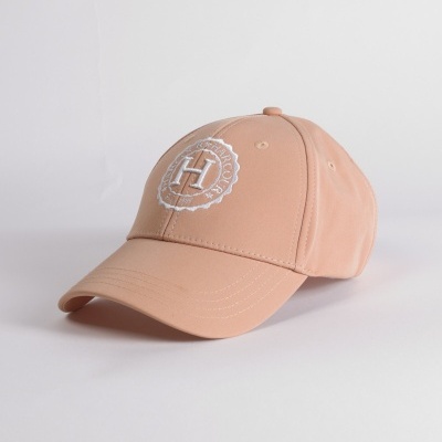 Boné cor bege claro com bordado branco, colocado numa superfície branca