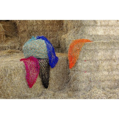 Redes coloridas penduradas sobre fardos de palha num celeiro