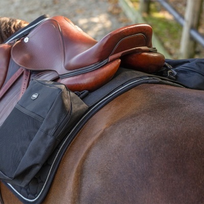 Selim de equitação castanho de couro com bolsa preta num cavalo castanho