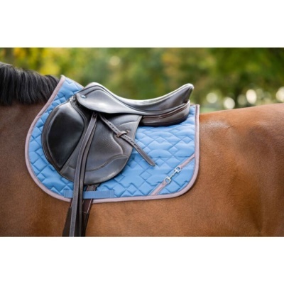 Sela preta de cavalo sobre manta azul e cavalo castanho