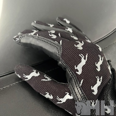 Luvas pretas com estampado branco de cães sobre superfície de couro escura