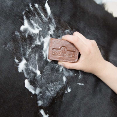 Sabão castanho com relevo a ser aplicado em pele de animal preta com espuma branca