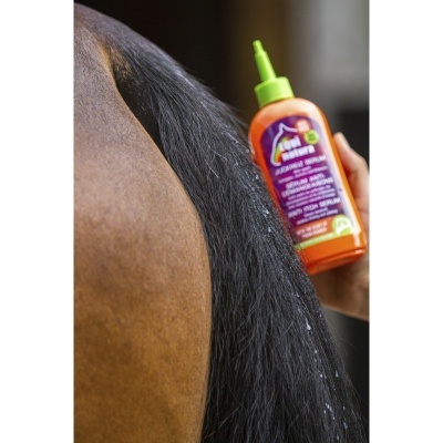 Frasco laranja e verde junto à cauda de cavalo castanho.