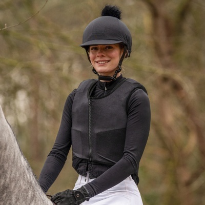 Mulher com vestuário de equitação sentado num cavalo cinza