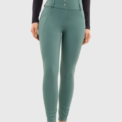 Calças justas verdes, top preto de manga comprida e ténis brancos num fundo cinzento