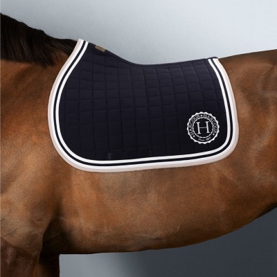 Tapete de sela azul escuro em cavalo castanho, com logo H branco