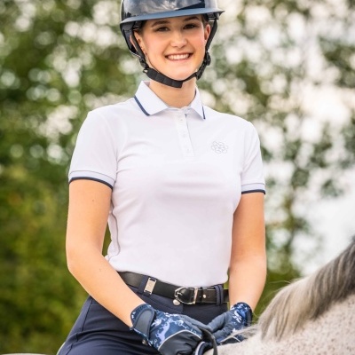 Mulher com roupa de equitação montada num cavalo cinzento ao ar livre