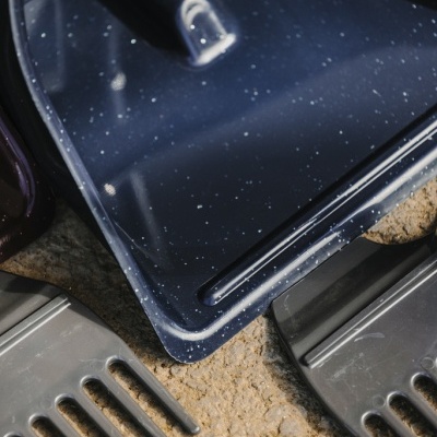 Pá azul e dois pentes pretos sobre areia clara