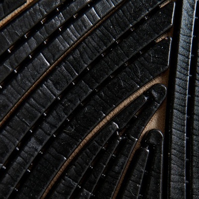 Superfície preta texturizada com linhas elevadas sobre fundo castanho