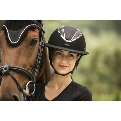 Mulher com capacete preto ao lado de cavalo castanho com bridão e protetor de orelhas