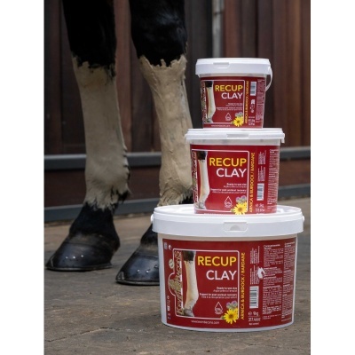 Três recipientes de argila para cavalos recup clay empilhados com fundo de pernas de cavalo