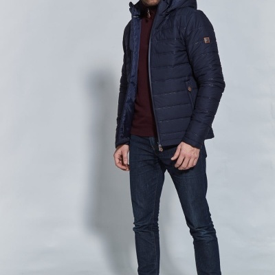 Homem com casaco acolchoado azul, jeans e sapatilhas brancas