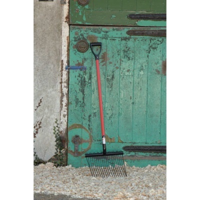 Ancinho de jardim com cabo vermelho encostado em porta verde desgastada