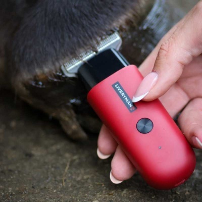 Aparelho cortador de pêlo vermelho com botão preto na mão