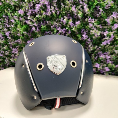 Capacete cinza fosco com placa prateada 'Casco 1955' e detalhes ventilação