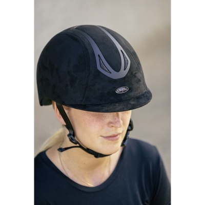 Capacete de equitação preto com detalhes cinzentos e cinto de segurança, usado por mulher.
