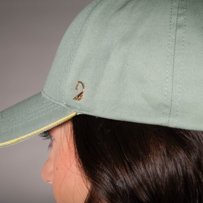 Boné verde claro com aplicação metálica dourada usado por pessoa.
