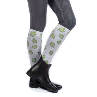 Meias brancas com estampa de abacate usadas com botas pretas e calças cinzentas.