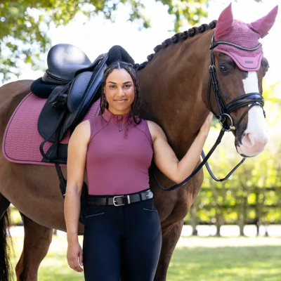 Cavaleira com colete lilás junto a cavalo castanho com abaixador e sela lilás
